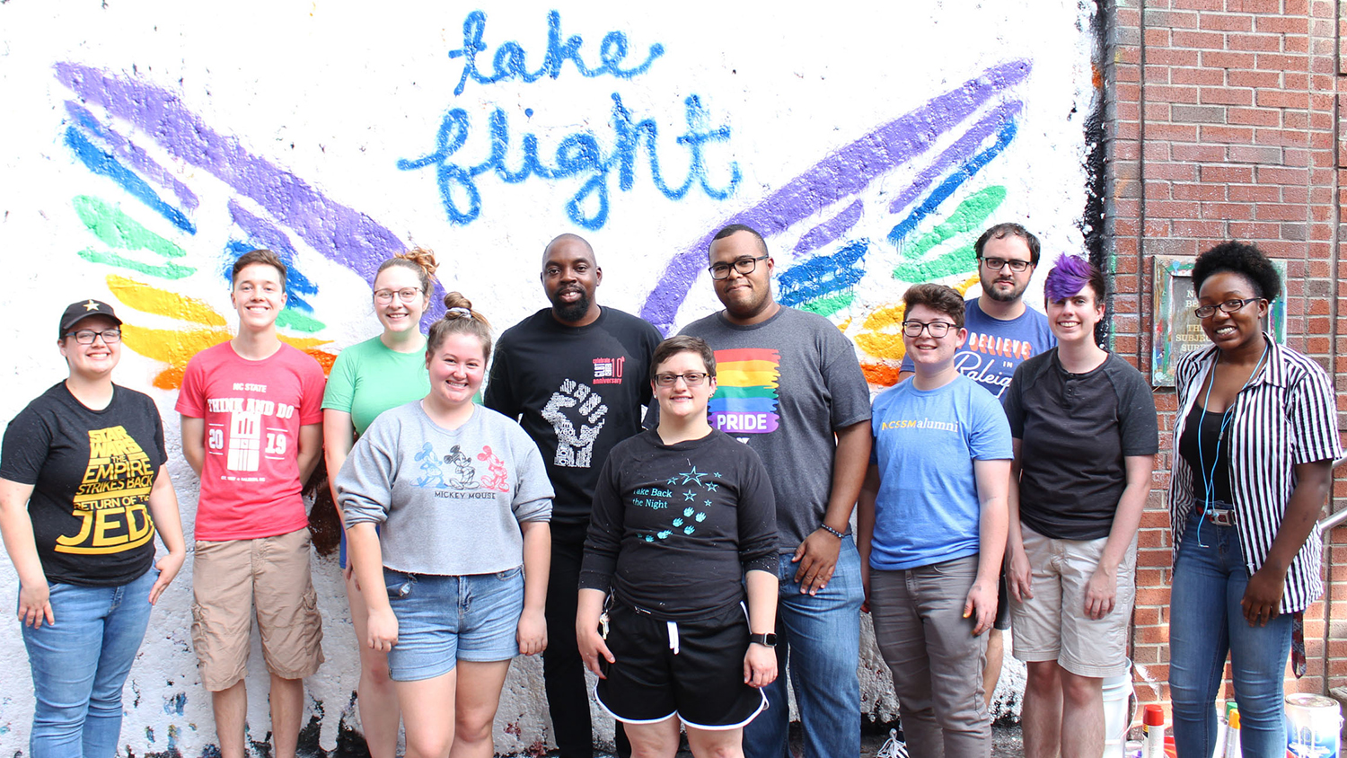 Students in front a mural that says Take Flight