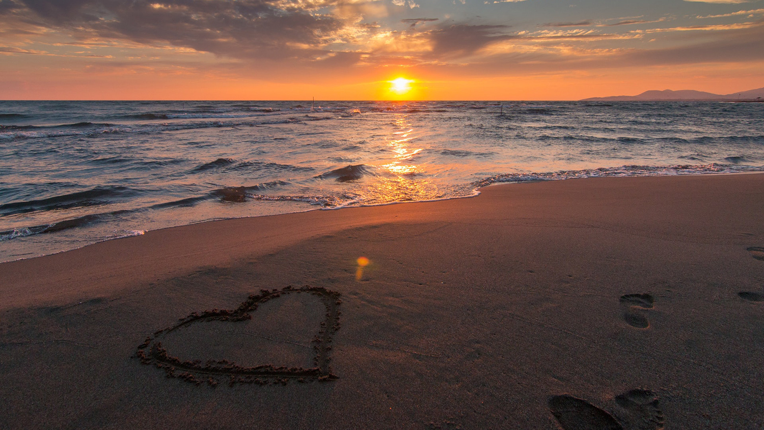 Beach sunset with heart drawn in the sand