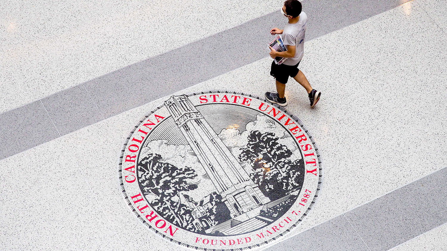 A student walks over the seal on the floor of Talley Student Union