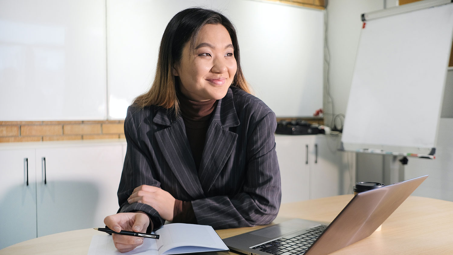Smiling Asian woman in an office with computer